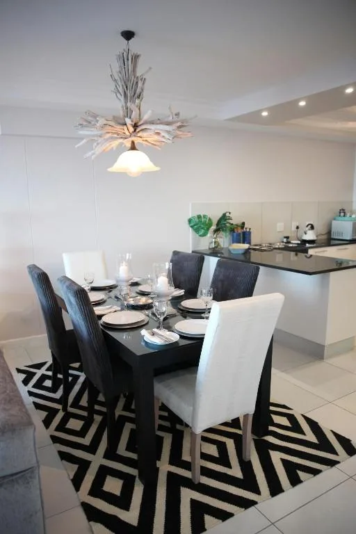Modern dining area with black table, upholstered chairs, and open kitchen