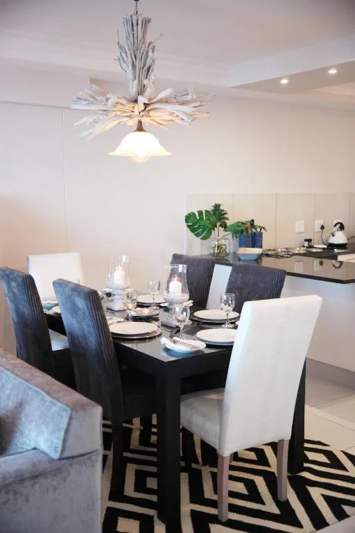Modern dining table set with black and white chairs under contemporary pendant light