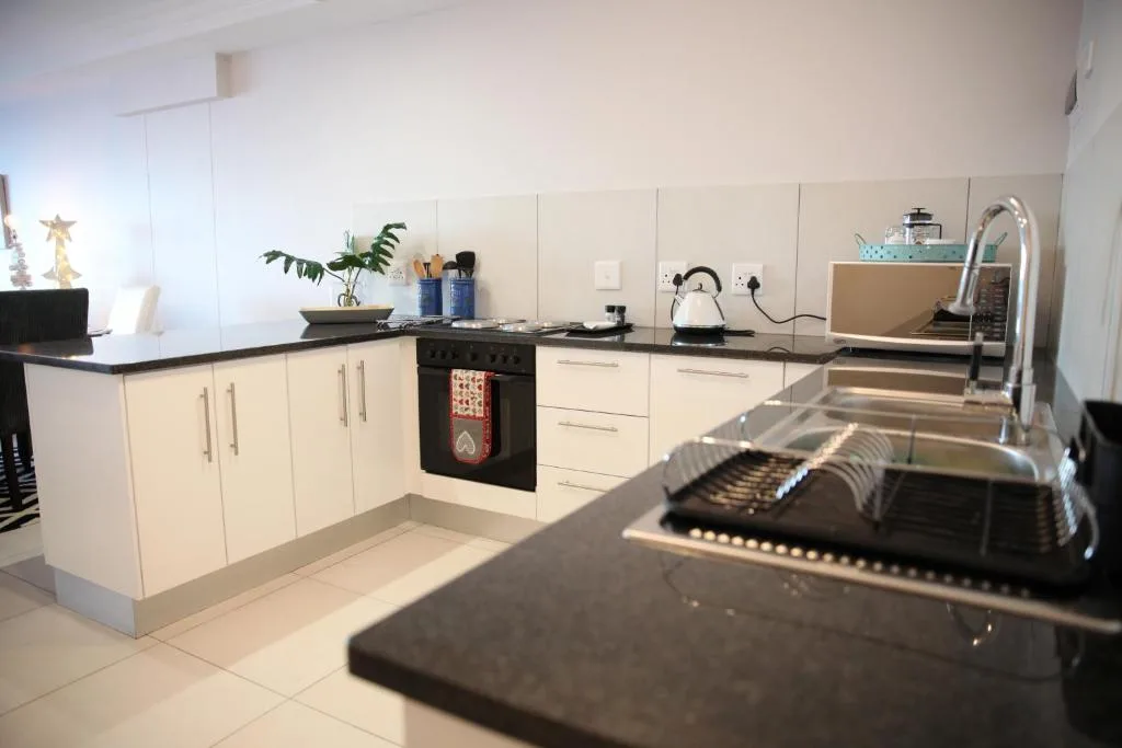 Modern kitchen with cream cabinetry, black countertop, and stainless steel appliances