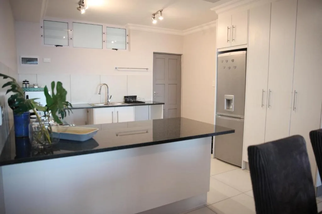 Modern kitchen with white cabinetry, black countertop, stainless steel appliances