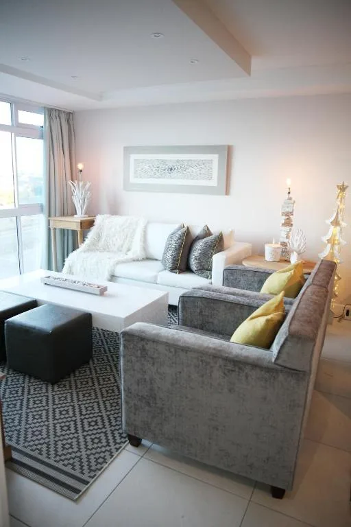 Modern living room with gray sofas, white coffee table, and large windows