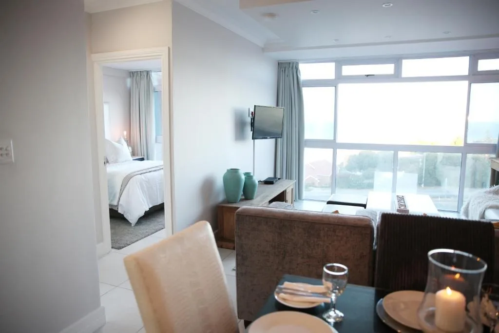 Modern lounge with brown sofa, wall-mounted TV, and large windows overlooking bay