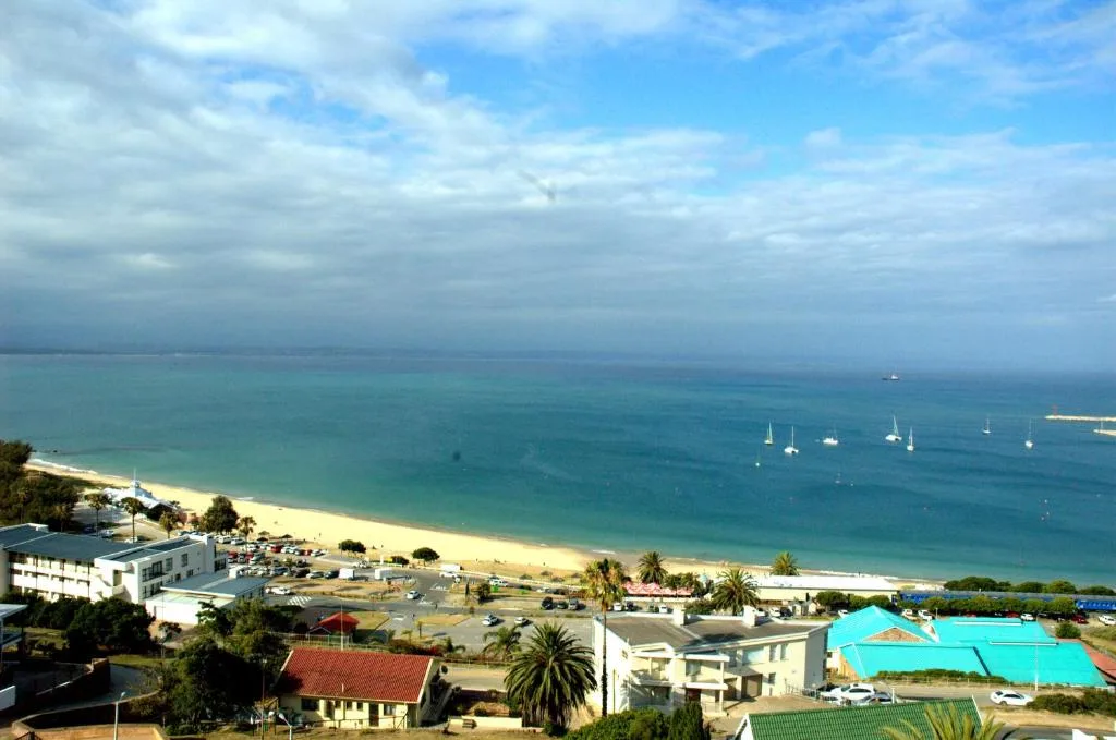 Stunning coastal bay view with golden beach, turquoise waters, and sailing boats
