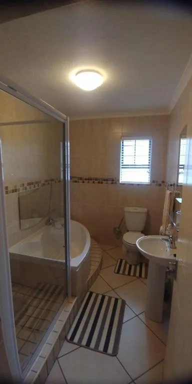 Modern bathroom with shower cubicle, toilet, vanity sink, and tiled flooring