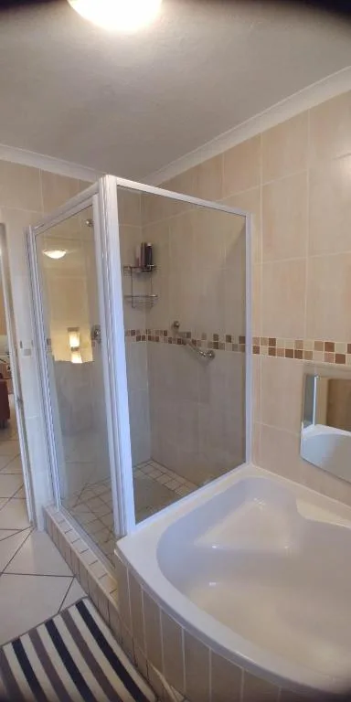 Modern bathroom with glass shower enclosure and white curved bathtub