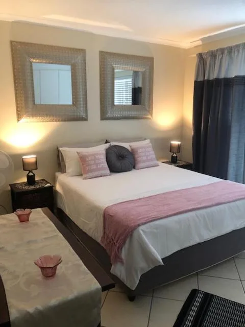 Spacious bedroom with queen bed, decorative mirrors, warm lighting, and modern furnishings