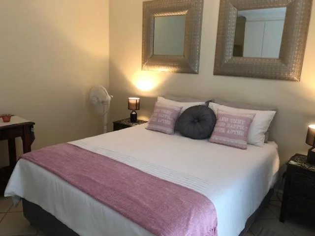 Comfortable double bed with purple accent throw and decorative pillows