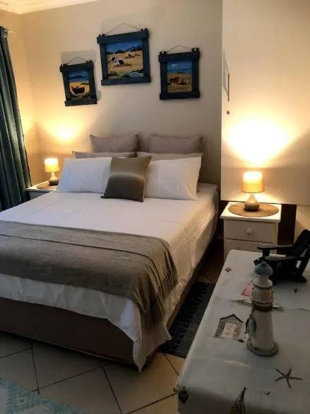 Spacious bedroom with queen bed, warm lighting, and framed wall art above headboard