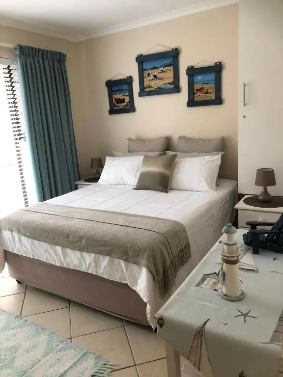 Spacious bedroom with queen bed, neutral bedding, and framed coastal artwork