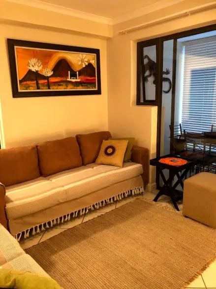 Cozy lounge with brown sofa, decorative artwork, and bright natural lighting