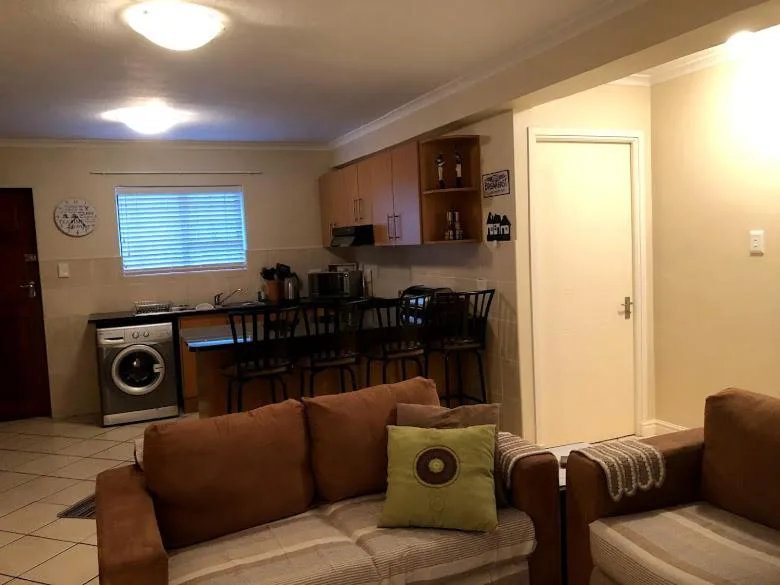 Open-plan living area with brown leather sofa and kitchen visible behind