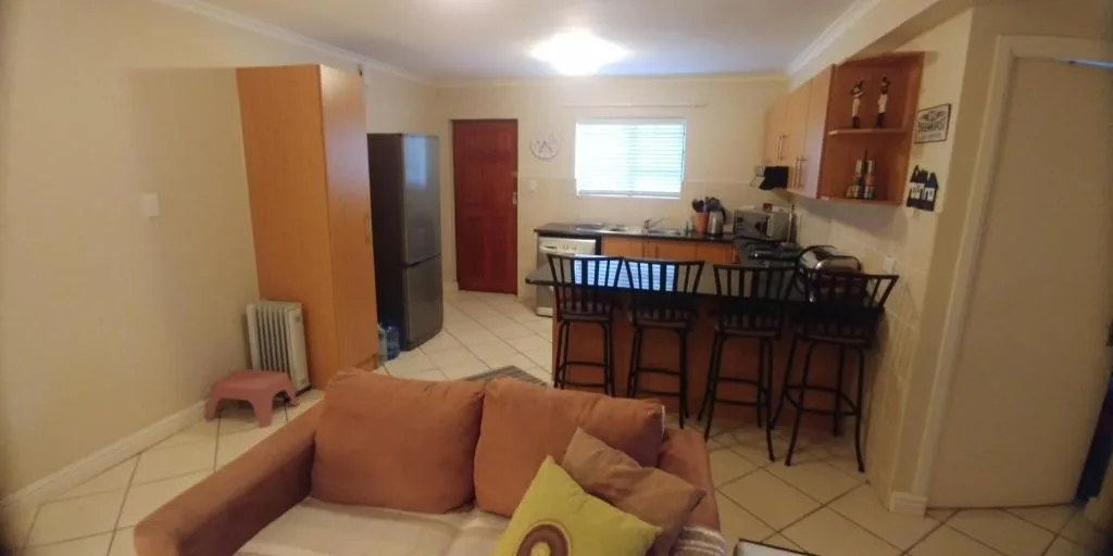 Open-plan lounge with orange sofa, kitchen counter and bar seating visible