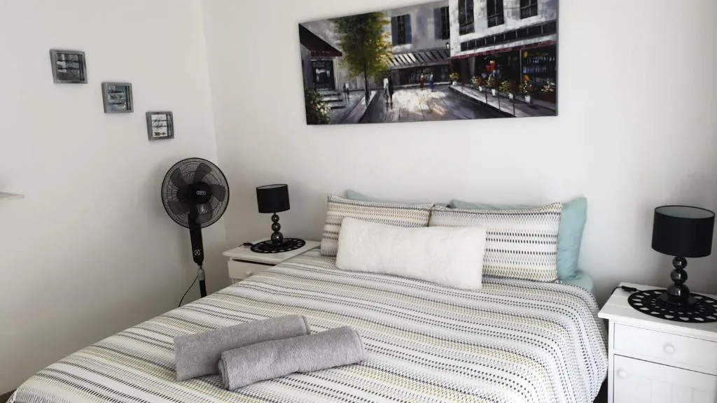 Bright bedroom with patterned bedding, pillows, and black bedside lamps