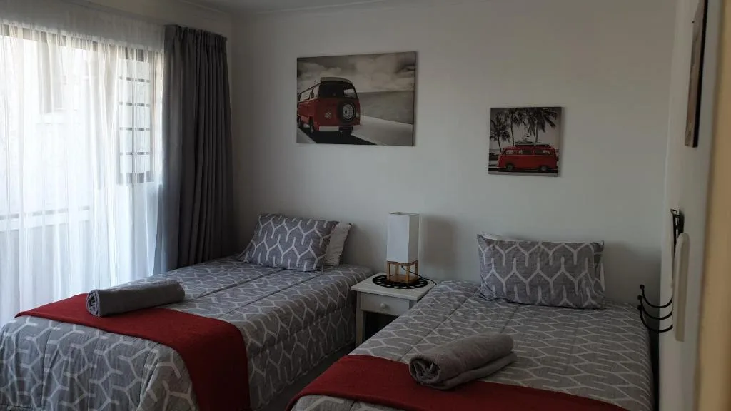 Twin bedroom with patterned bedding, vintage van artwork, and sheer curtains