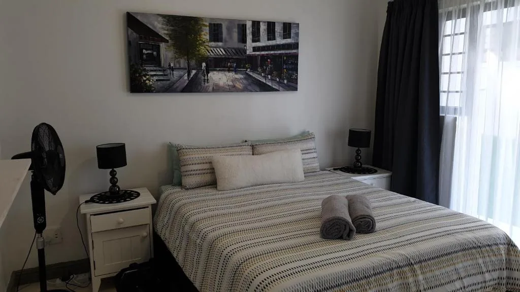 Bedroom with striped bedding, pillows, rolled towels, and modern decor