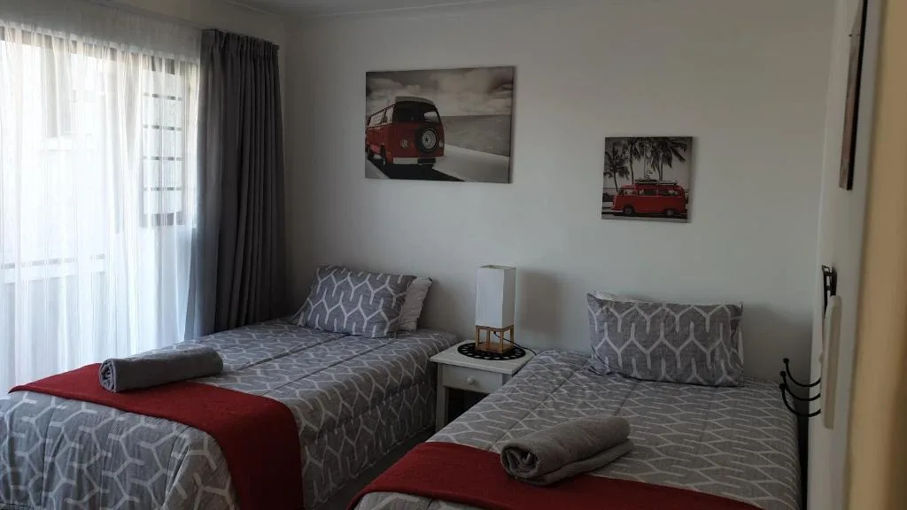Twin bedroom with patterned bedding, vintage car artwork, and sheer curtains