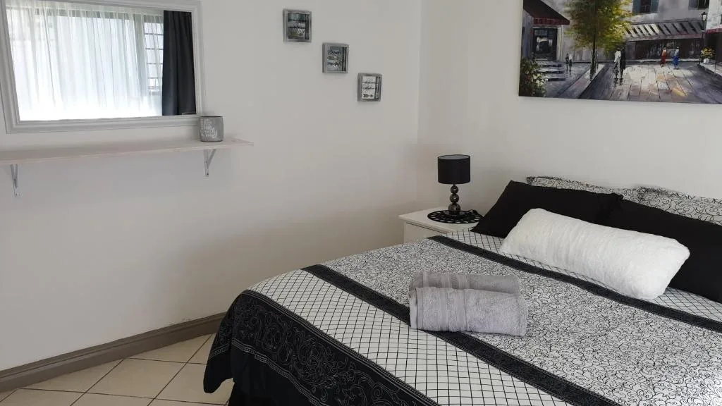 Modern bedroom with double bed, black and white bedding, bedside lamp, and window