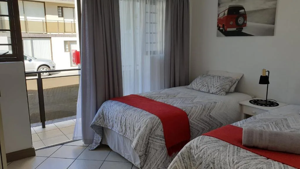 Twin beds with red runners and patterned bedding in bright bedroom