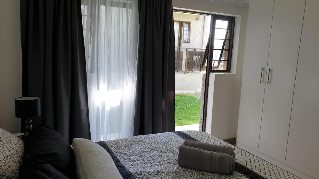 Modern bedroom with garden access through glass doors and built-in wardrobes