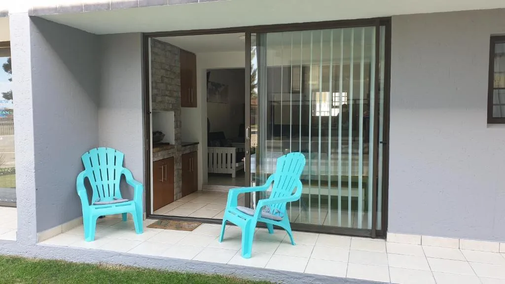 Turquoise Adirondack chairs on paved patio with sliding glass doors