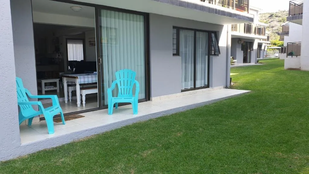 Bright turquoise chairs on paved patio overlooking manicured lawn