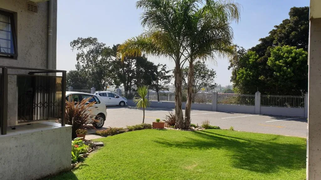 Property driveway with manicured lawn, palm trees, and parked vehicles