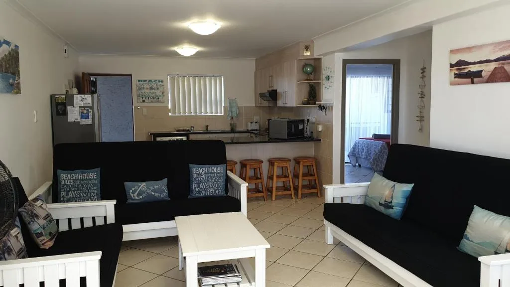 Open-plan lounge with black and white sofas, kitchen visible behind