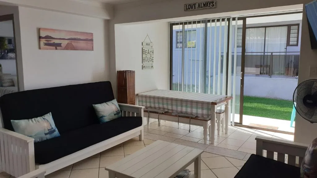 Bright lounge with black sofa, dining table, and patio doors opening to garden