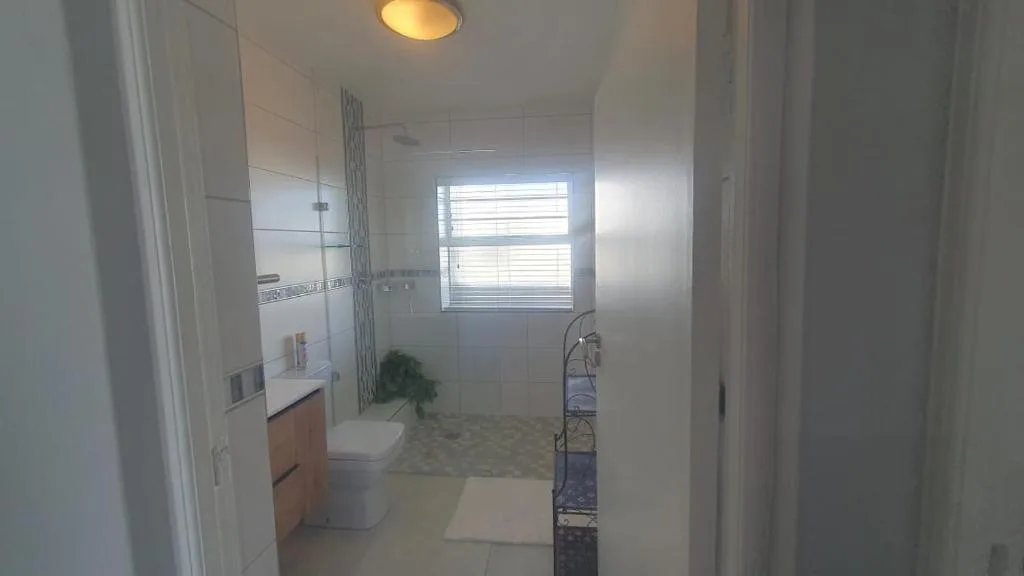 Modern bathroom with vanity, toilet, shower enclosure, and window