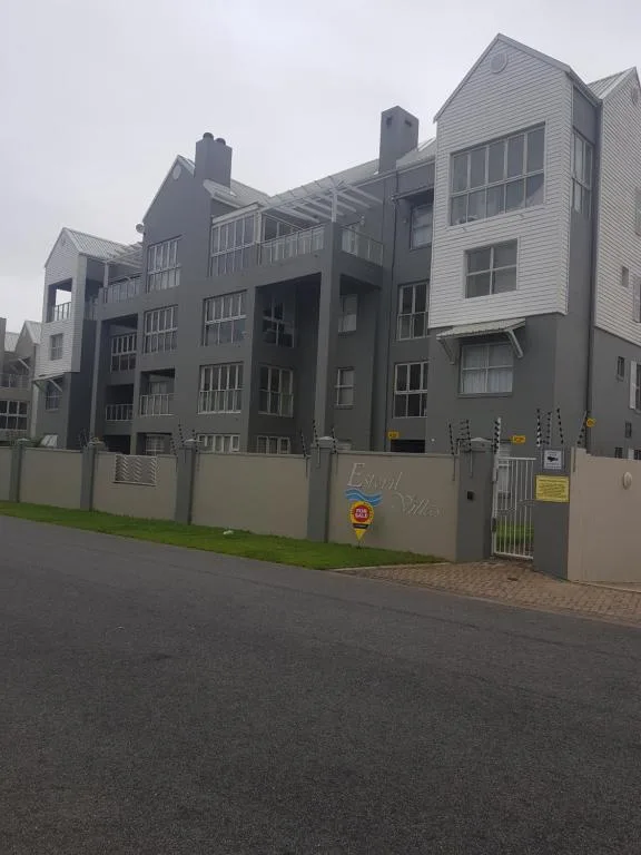 Modern multi-story apartment building with gray facade and secure perimeter wall