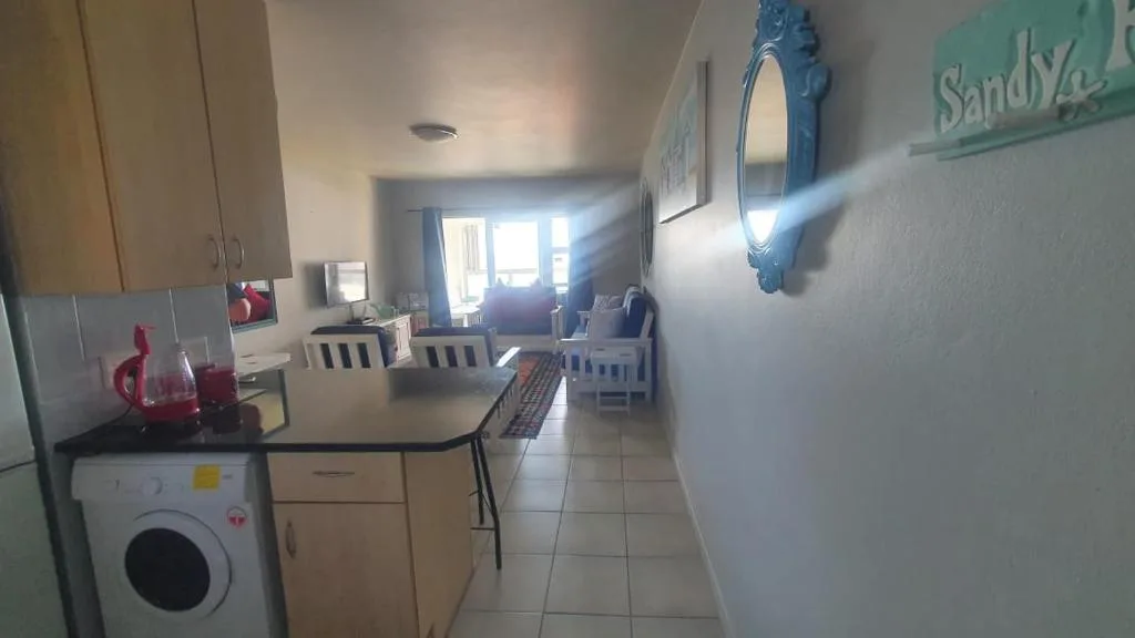 Kitchen with washing machine, counters, and view into lounge area