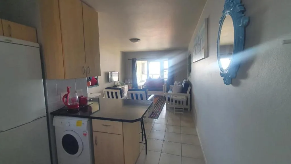 Open-plan kitchen with wooden cabinetry, washing machine, and dining area beyond