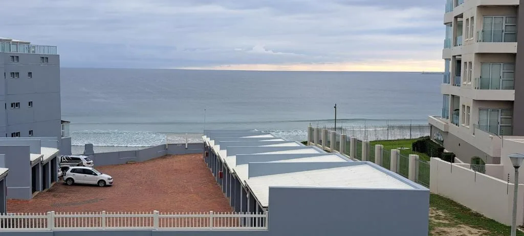 Panoramic ocean view from beachfront property with apartment buildings and parked car