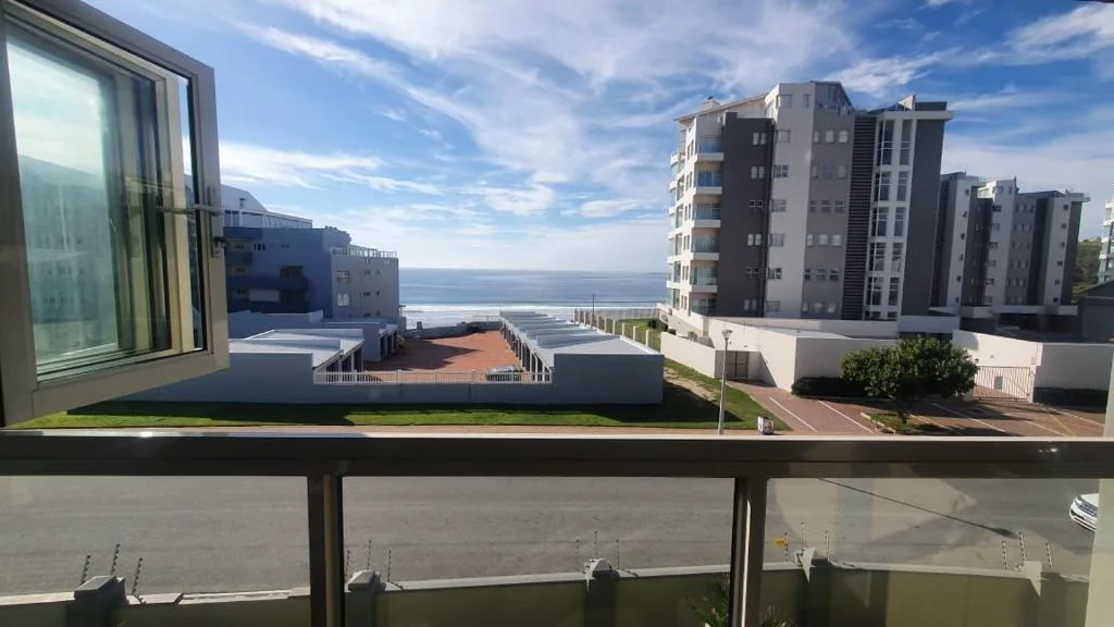 Ocean and coastal town view from apartment balcony with modern buildings