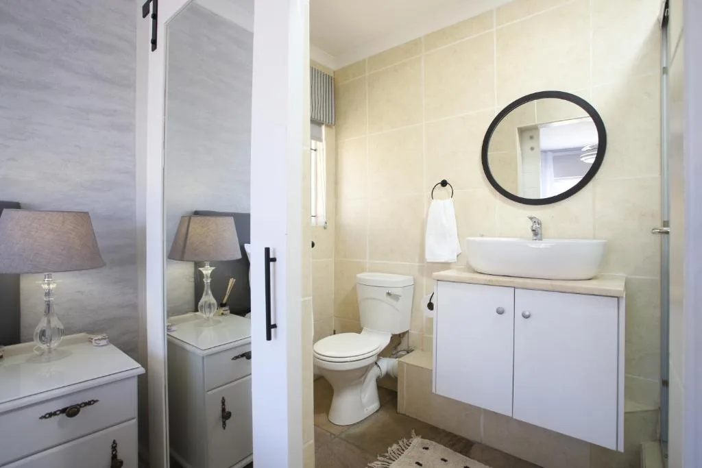 Modern bathroom with round mirror, white vessel sink, and toilet