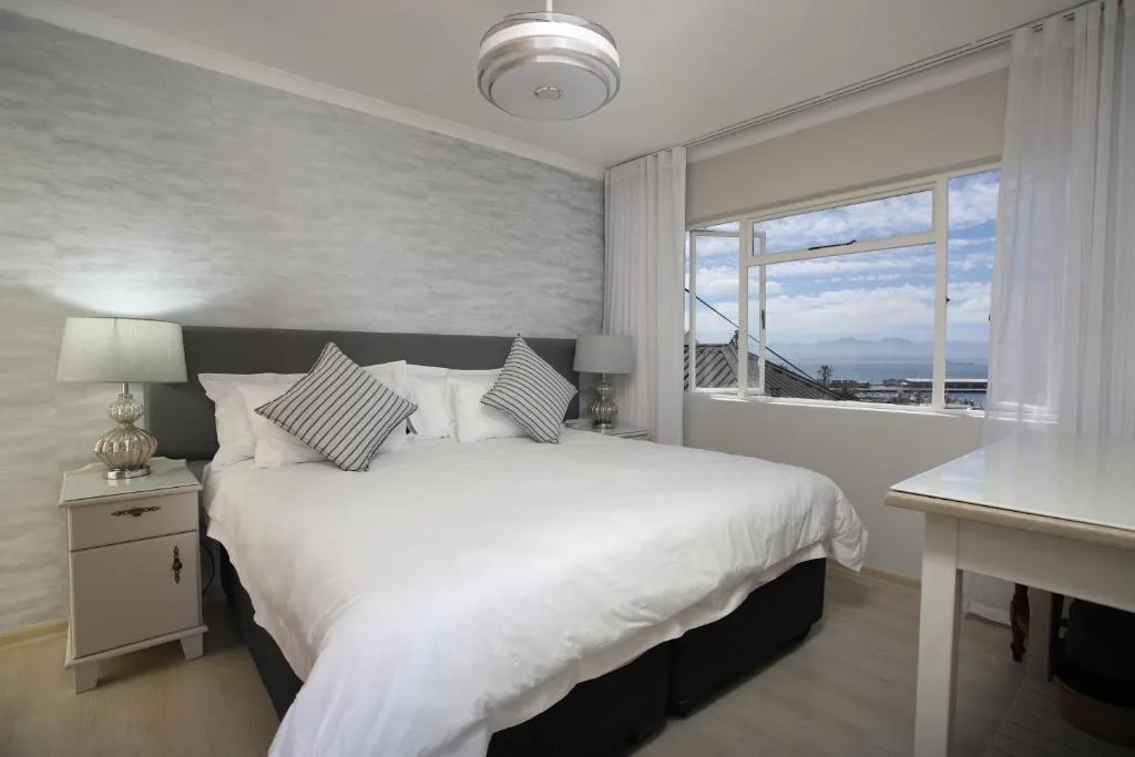 Bright modern bedroom with ocean and mountain views through large windows