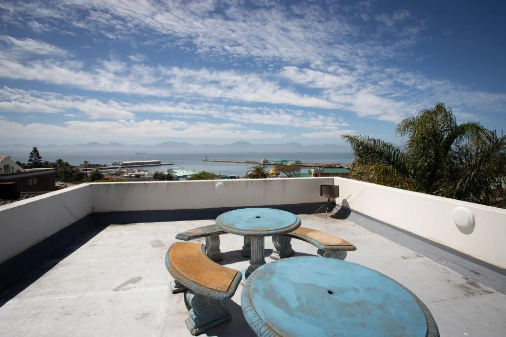 Rooftop deck with picnic tables overlooking Mossel Bay harbor and mountains