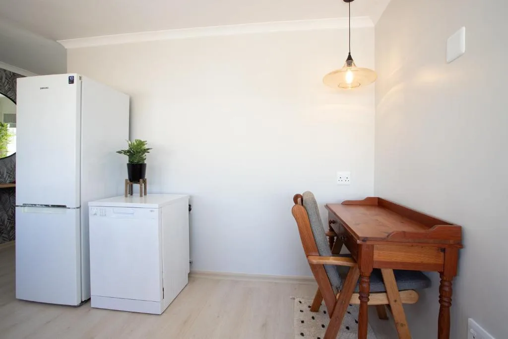 Modern kitchen-dining area with white appliances and wooden desk