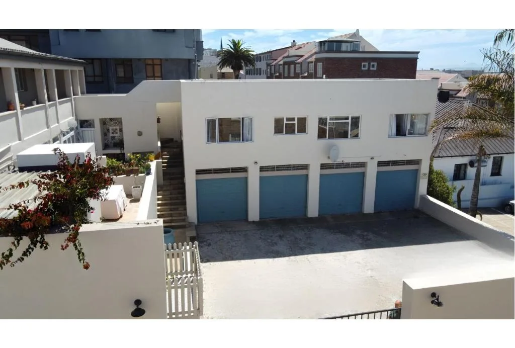 Modern white residential building with blue garage doors and manicured gardens