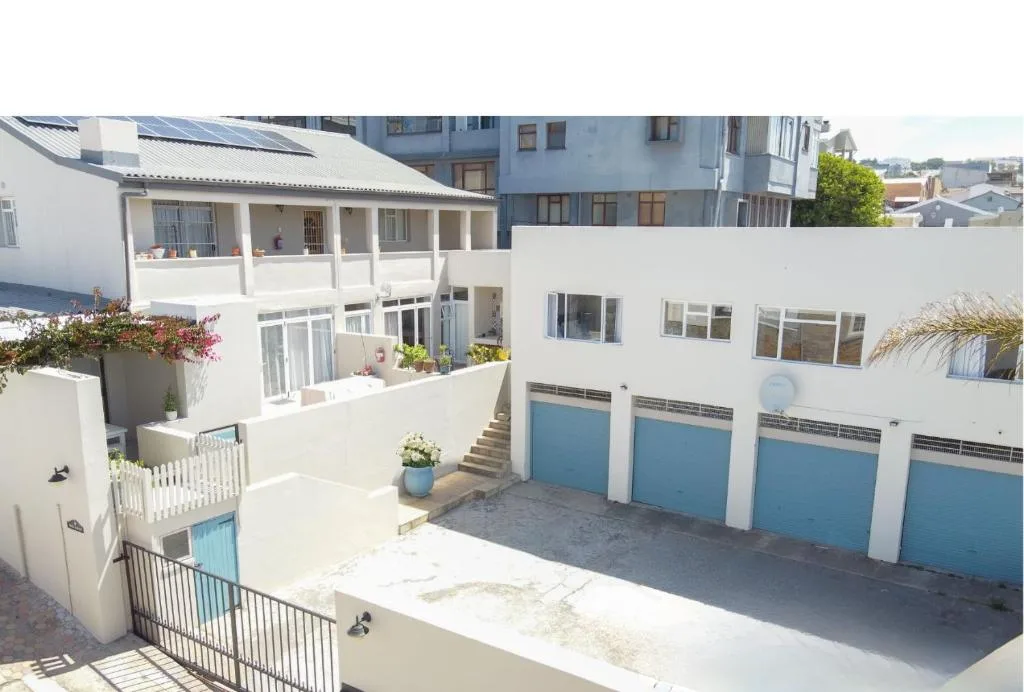 White modern apartment building with blue garage doors and coastal gardens