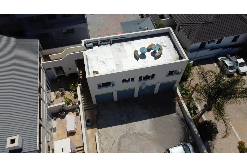 Modern white apartment building with rooftop deck and surrounding gardens