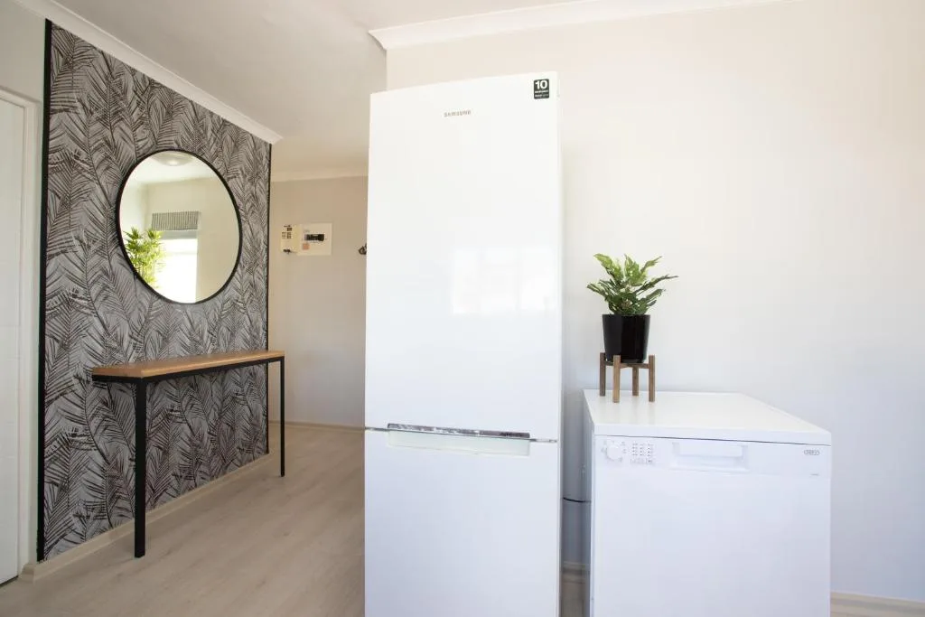 Modern kitchen with white refrigerator, washing machine, and decorative mirror accent