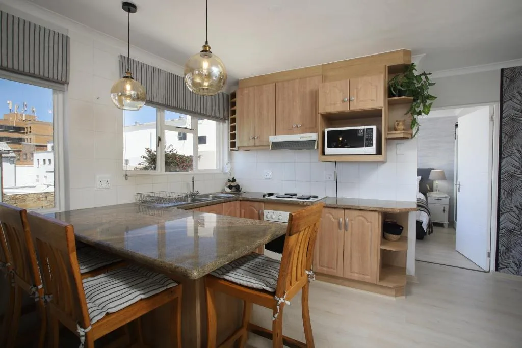 Modern kitchen with wooden cabinetry, granite countertop island, and pendant lighting