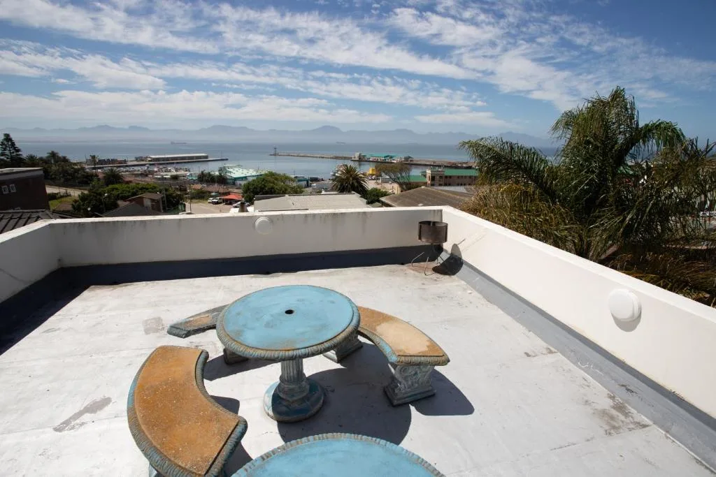 Scenic coastal vista with mountains, harbor, and ocean from rooftop seating area