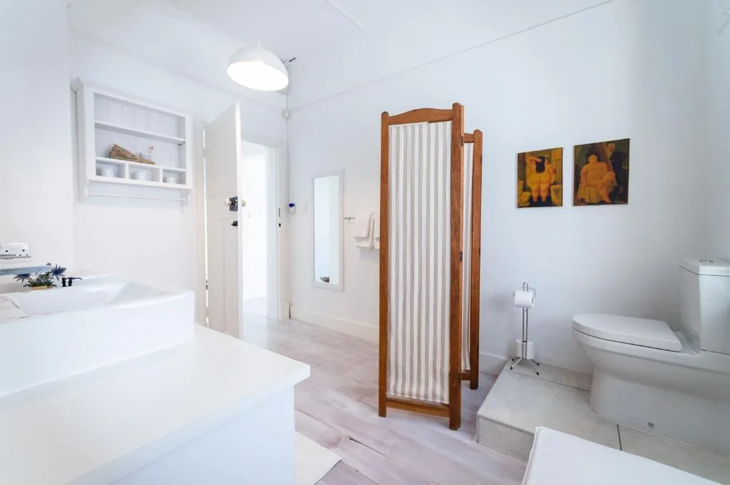 Bright modern bathroom with dual vanities, freestanding tub, and toilet
