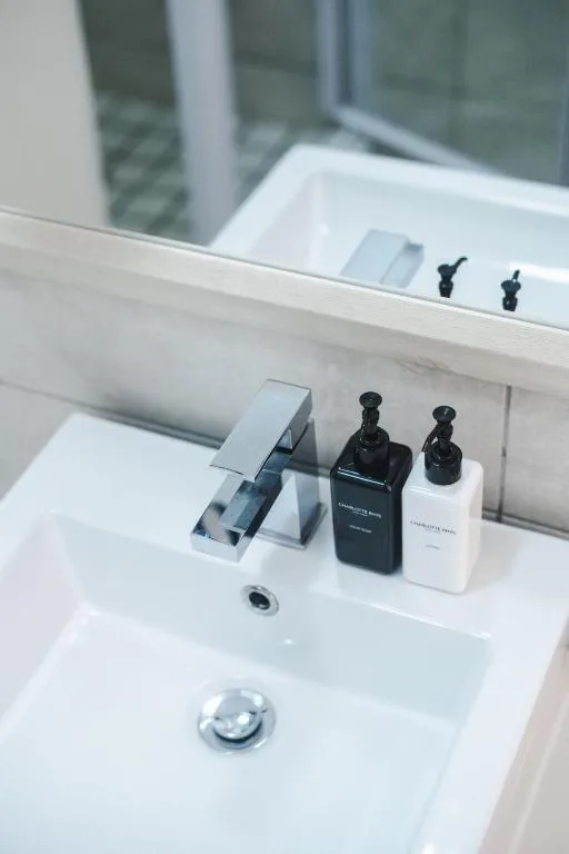 Modern bathroom vanity with white sink, chrome faucet, and amenity bottles