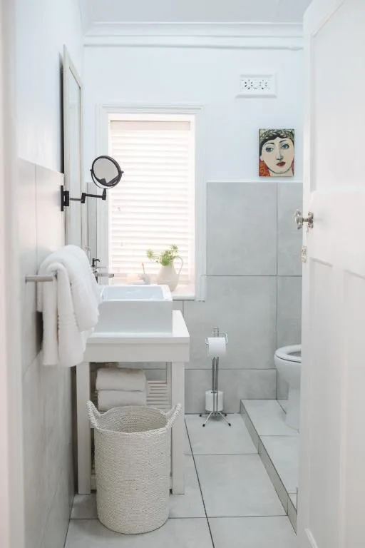 Bright modern bathroom with white vanity, grey tile shower enclosure