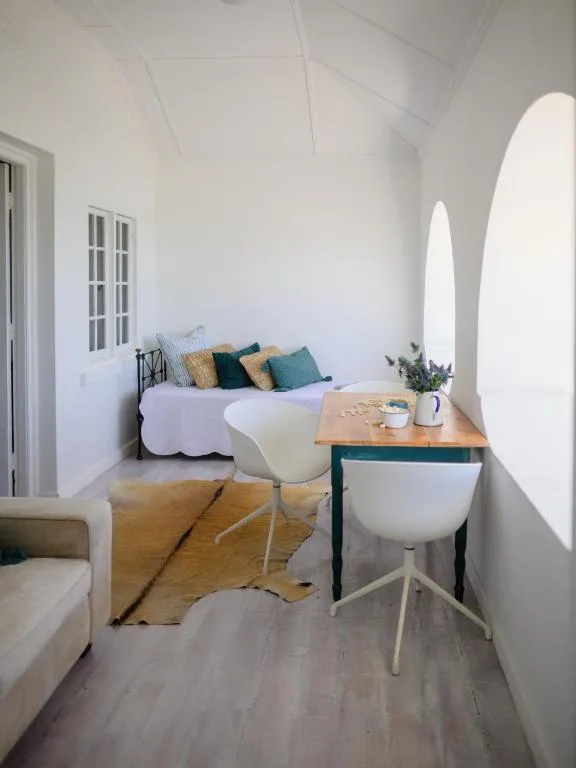 Bright bedroom with bed, colorful pillows, desk, and arched windows