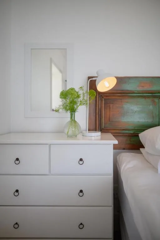 Bedside table with fresh flowers and warm lamp in bedroom