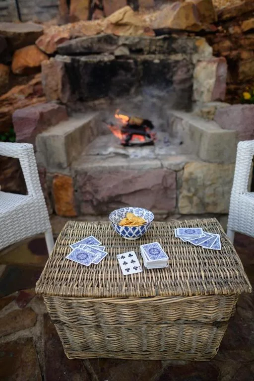 Outdoor braai area with woven seating and active fireplace pit